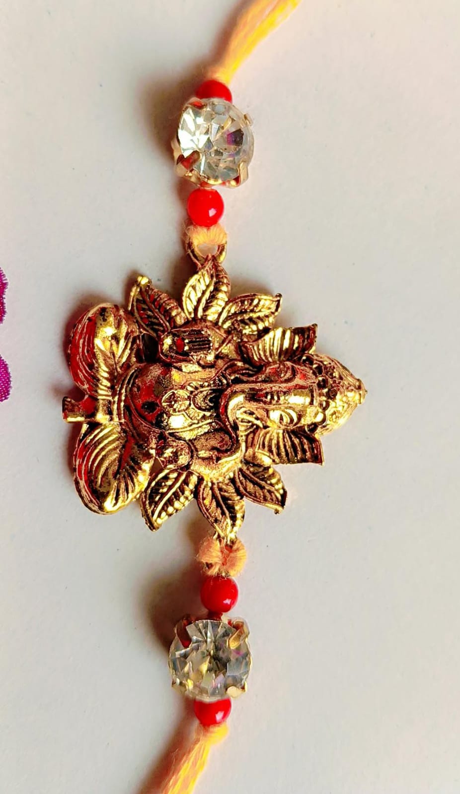 Handmade Ganesha Rakhi – Golden Finish with Red Beads & Crystal Stones (Single Piece)
