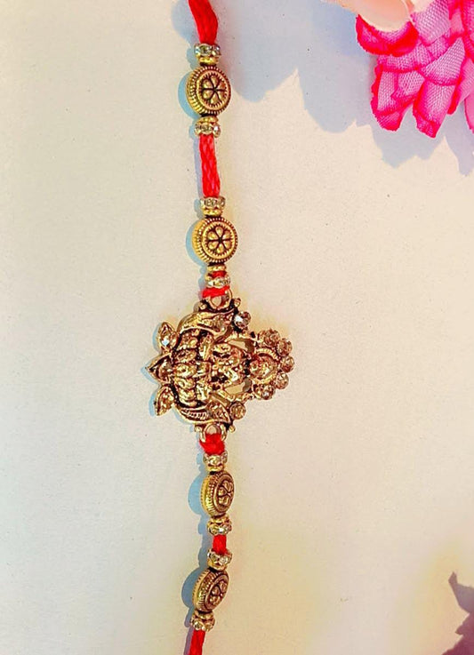 Handmade Devi Lakshmi Rakhi – Antique Gold Charm with Chakra Beads & Red Thread (Single Piece)