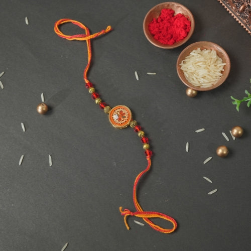 Handmade Rakhi – Traditional Orange Thread Rakhi with Circular Beaded Centerpiece