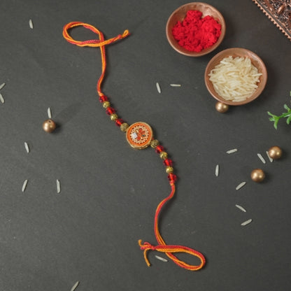 Handmade Rakhi – Traditional Orange Thread Rakhi with Circular Beaded Centerpiece