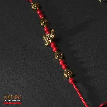 Antique Krishna Rakhi with Brass Murli Motif and Red Beaded Thread – Handmade Rakhi for Brother